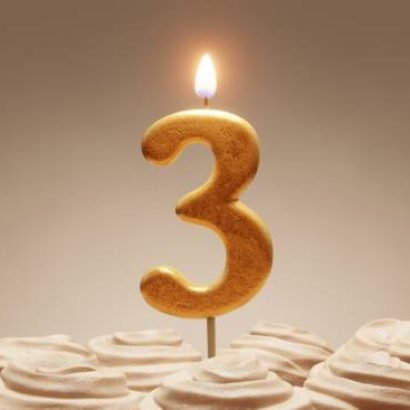 3rd birthday or anniversary celebration. Lit golden number candle on cake with icing in neutral tones. 3D rendering